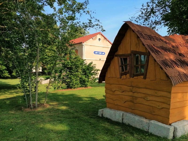 Charmante cabane en bois avec un toit en ardoise, entourée de verdure.