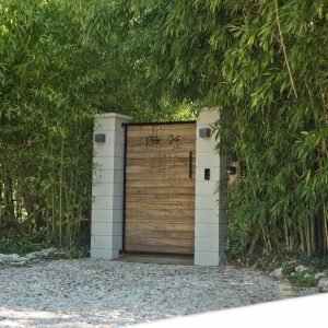 Entrée dune villa moderne entourée de bambous luxuriants et dun chemin en gravier.