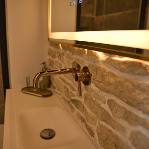 Salle de bain moderne dans un hébergement touristique, avec un lavabo en pierre et un éclairage