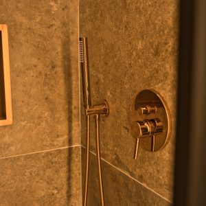 Salle de bain moderne avec douche en marbre et robinetterie dorée élégante.