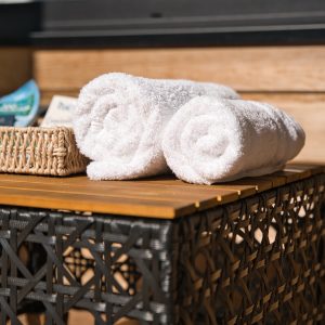 Hébergement de luxe avec serviettes blanches soigneusement enroulées sur une table en osier.