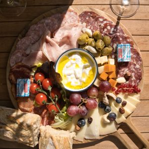 Plateau de charcuterie dans un gîte, avec fromages, olives et tomates cerises.