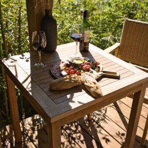 Table en bois avec un repas gourmet et vin, vue sur la rivière. Idéal pour un séjour romantique.