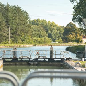 Écluse paisible au bord dun canal, entourée de verdure et de nature.