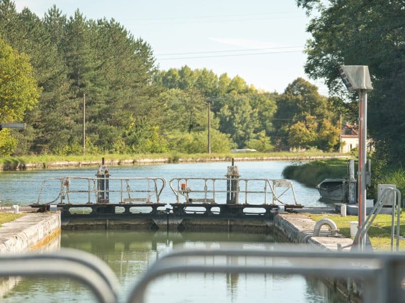Écluse paisible au bord dun canal, entourée de verdure et de nature.