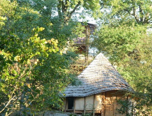 Cabane en bois au milieu de la nature, avec un toit en pente et entourée darbres.