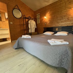 Chalet en bois chaleureux avec lit double, salle de bain moderne et décoration cosy.