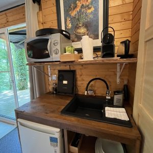 Cuisine équipée dans un chalet en bois, avec un évier, un micro-ondes et un accès à la terrasse.