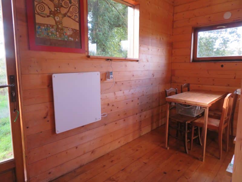 Cabane en bois chaleureuse avec un intérieur lumineux et une table en bois près de la fenêtre.