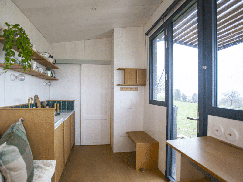 Cabane moderne avec cuisine intégrée et vue sur la nature. Ambiance chaleureuse et lumineuse.