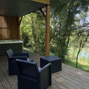 Hébergement insolite : chalet en bois avec terrasse, jacuzzi et vue sur la nature verdoyante.