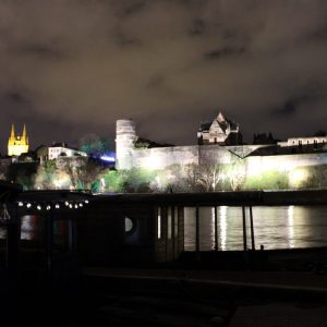 Hébergement insolite sur une péniche, vue nocturne du château illuminé et des nuages.