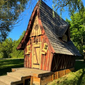 Charmante cabane en bois avec un toit pentu et des fenêtres colorées.