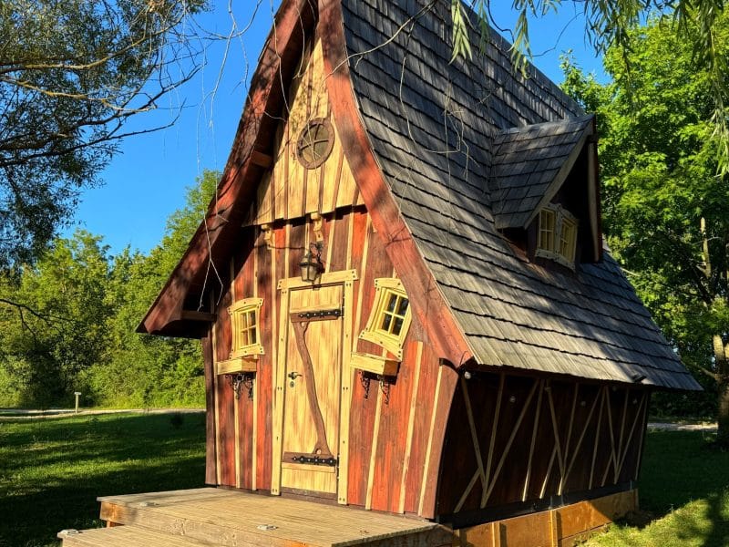 Charmante cabane en bois avec un toit pentu et des fenêtres colorées.