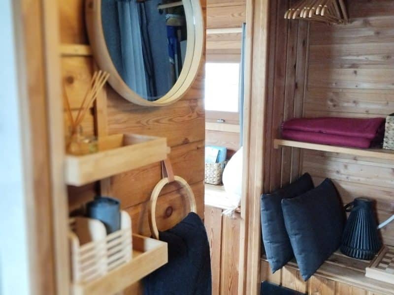 Cabane en bois avec miroir rond et étagères élégantes pour un séjour confortable.