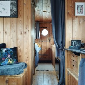 Intérieur chaleureux d'un hébergement insolite en bois, avec des murs en pin et une ambiance cosy.