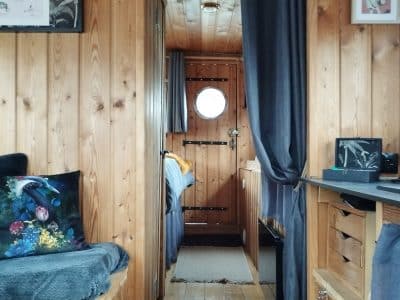 Intérieur chaleureux d'un hébergement insolite en bois, avec des murs en pin et une ambiance cosy.