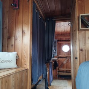 Intérieur chaleureux d'un hébergement insolite en bois, avec des rideaux et un lit douillet.