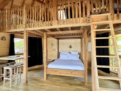 Cabane en bois avec lit douillet, mezzanine et décoration chaleureuse. Ambiance nature.