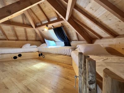 Chalet en bois avec lits superposés, ambiance chaleureuse et toit en pente. Parfait pour se