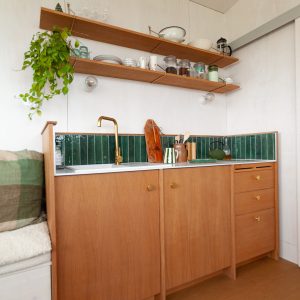 Cuisine moderne en hébergement insolite, avec des étagères en bois et des carreaux verts.