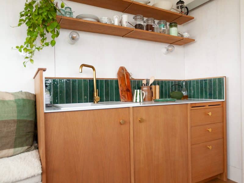 Cuisine moderne en hébergement touristique, avec étagères en bois et carrelage vert.
