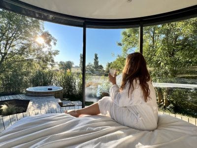 Séjournez dans un dôme transparent avec vue sur la nature, jacuzzi et lumière du matin.