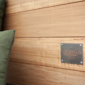 Hébergement insolite : un cocon en bois avec coussins verts, idéal pour une escapade relaxante.