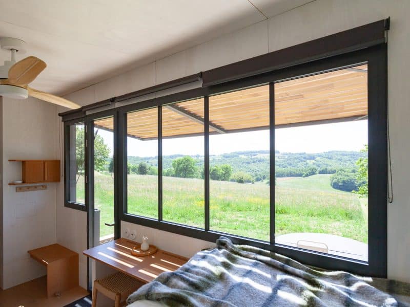 Cabane moderne avec grandes fenêtres offrant une vue panoramique sur la nature.