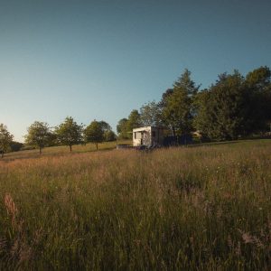 Un charmant chalet en pleine nature, entouré de champs verdoyants et d'arbres.