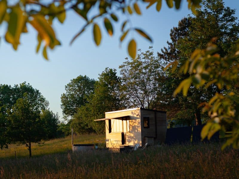Cabane en bois lumineuse, entourée de verdure et de arbres. Idéale pour un séjour nature.