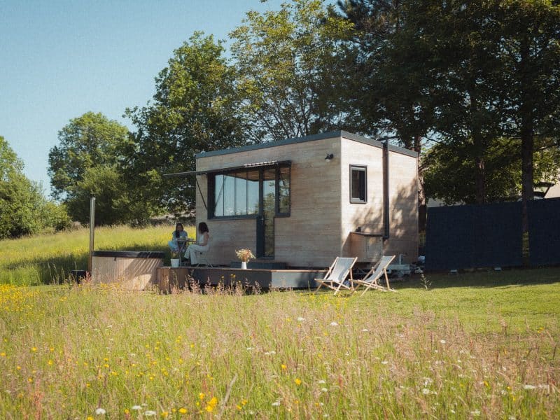 Charmante tiny house en bois, entourée de fleurs sauvages et dun espace détente.