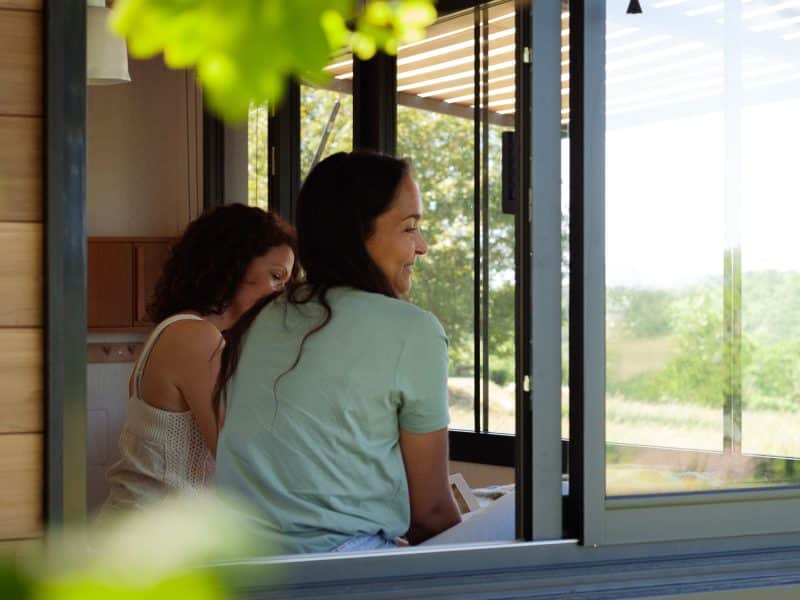 Deux amies se détendent dans un hébergement moderne avec vue sur la nature.