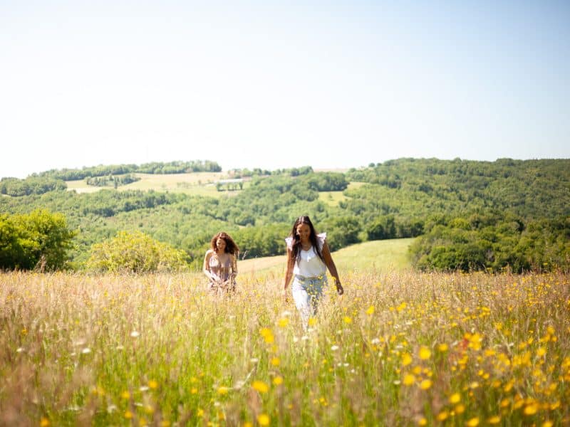 Deux amies se promènent dans un champ fleuri près dun gîte rural.