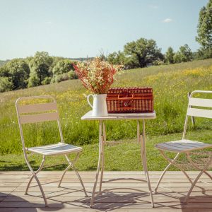 Charmant hébergement insolite avec une terrasse en bois, table décorée de fleurs et panier
