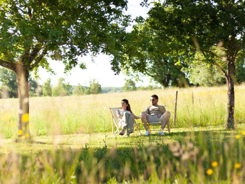 Couple détendu dans des chaises longues, au milieu dun champ verdoyant.