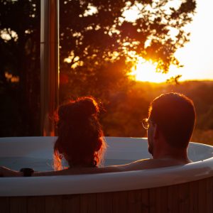 Bain nordique en pleine nature, couple admirant un coucher de soleil doré.