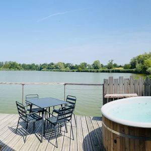 Hébergement insolite avec jacuzzi sur une terrasse en bois, vue imprenable sur le lac.