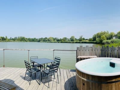 Hébergement insolite avec jacuzzi sur une terrasse en bois, vue imprenable sur le lac.