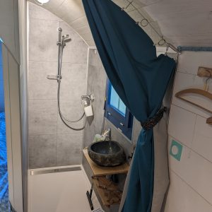 Salle de bain dun hébergement insolite avec douche moderne et décor naturel.