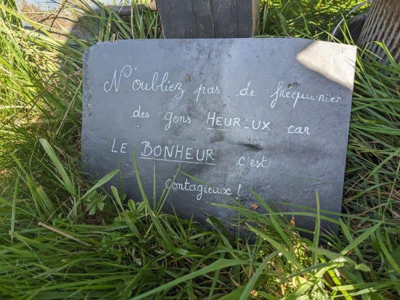 Gîte rural avec une jolie pancarte en ardoise sur lherbe verdoyante.