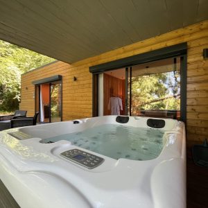 Hébergement insolite avec jacuzzi, entouré de verdure et de bois, offrant une ambiance relaxante.