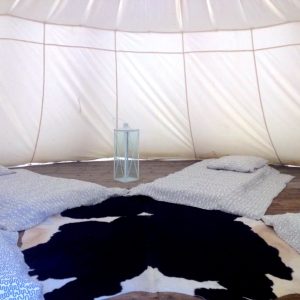 Tente de glamping spacieuse avec matelas confortables et décoration en peau de vache.