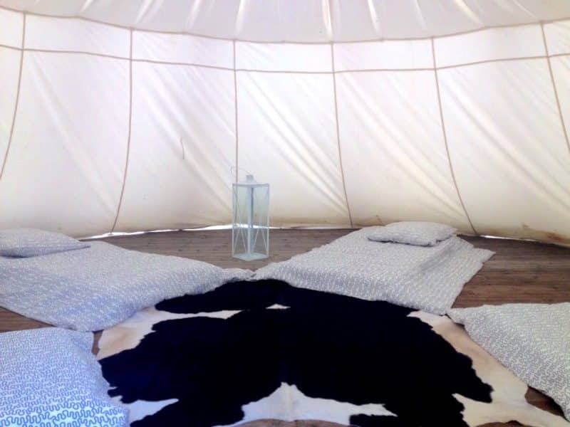 Tente de glamping spacieuse avec matelas confortables et décoration en peau de vache.