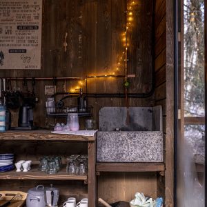 Un charmant cabanon en bois avec un coin cuisine rustique, éclairé par des guirlandes lumineuses.