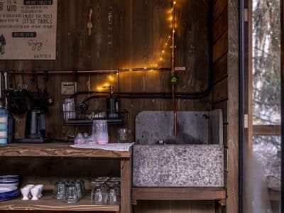 Un charmant cabanon en bois avec un coin cuisine rustique, éclairé par des guirlandes lumineuses.