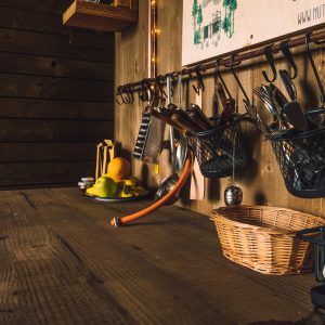Cuisine rustique d'un chalet, avec des ustensiles suspendus et des fruits frais sur la table.
