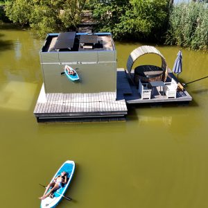 Cabane flottante moderne avec terrasse et kayak sur leau calme.