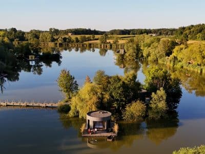 Cabane flottante sur un lac, entourée de verdure et d'un paysage paisible.