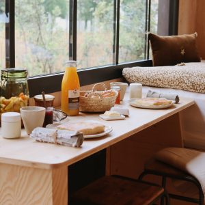 Un hébergement insolite avec une vue panoramique, petit-déjeuner copieux sur une table en bois.
